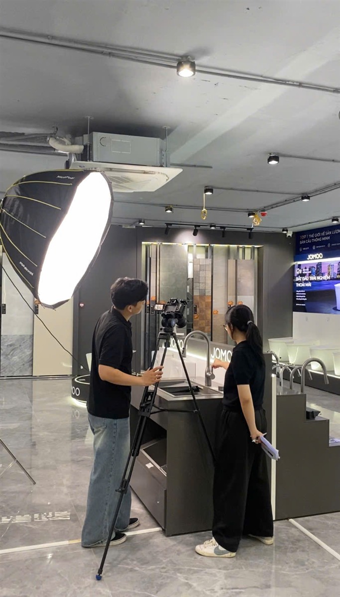 Ghi hình video tại showroom JOMOO với đèn tản sáng và máy quay trên chân máy.