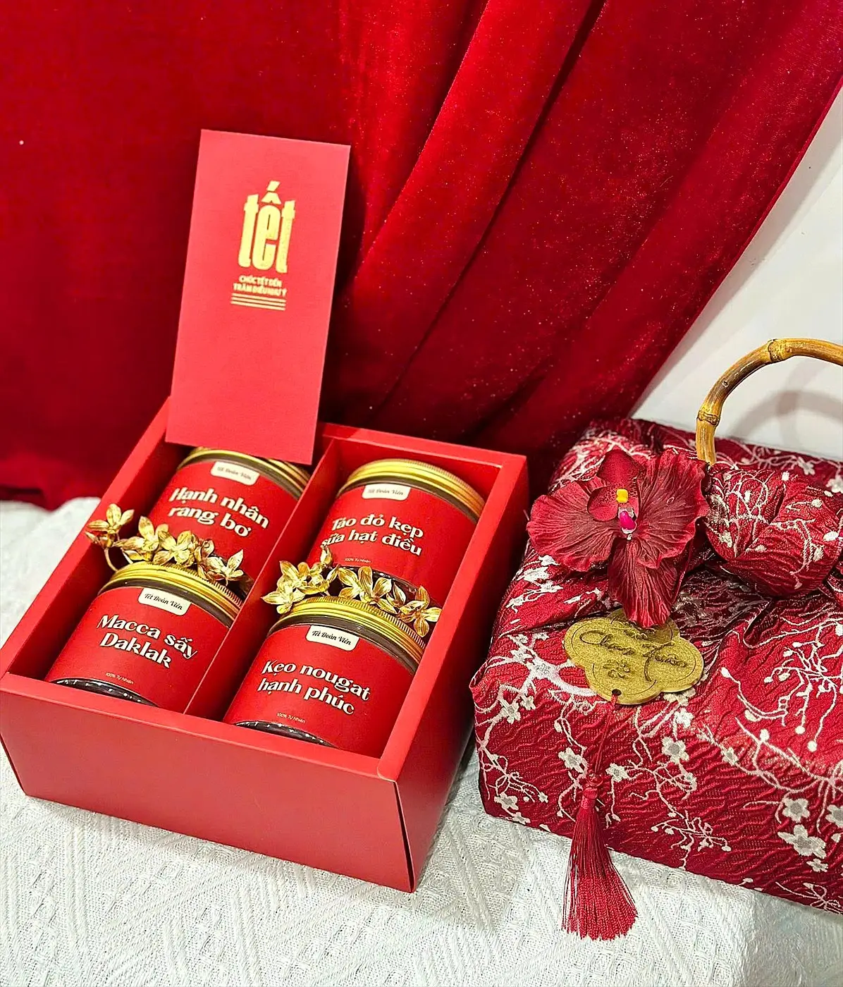 Red Tet gift box with four jars of nuts and dried fruit and a lucky money envelope