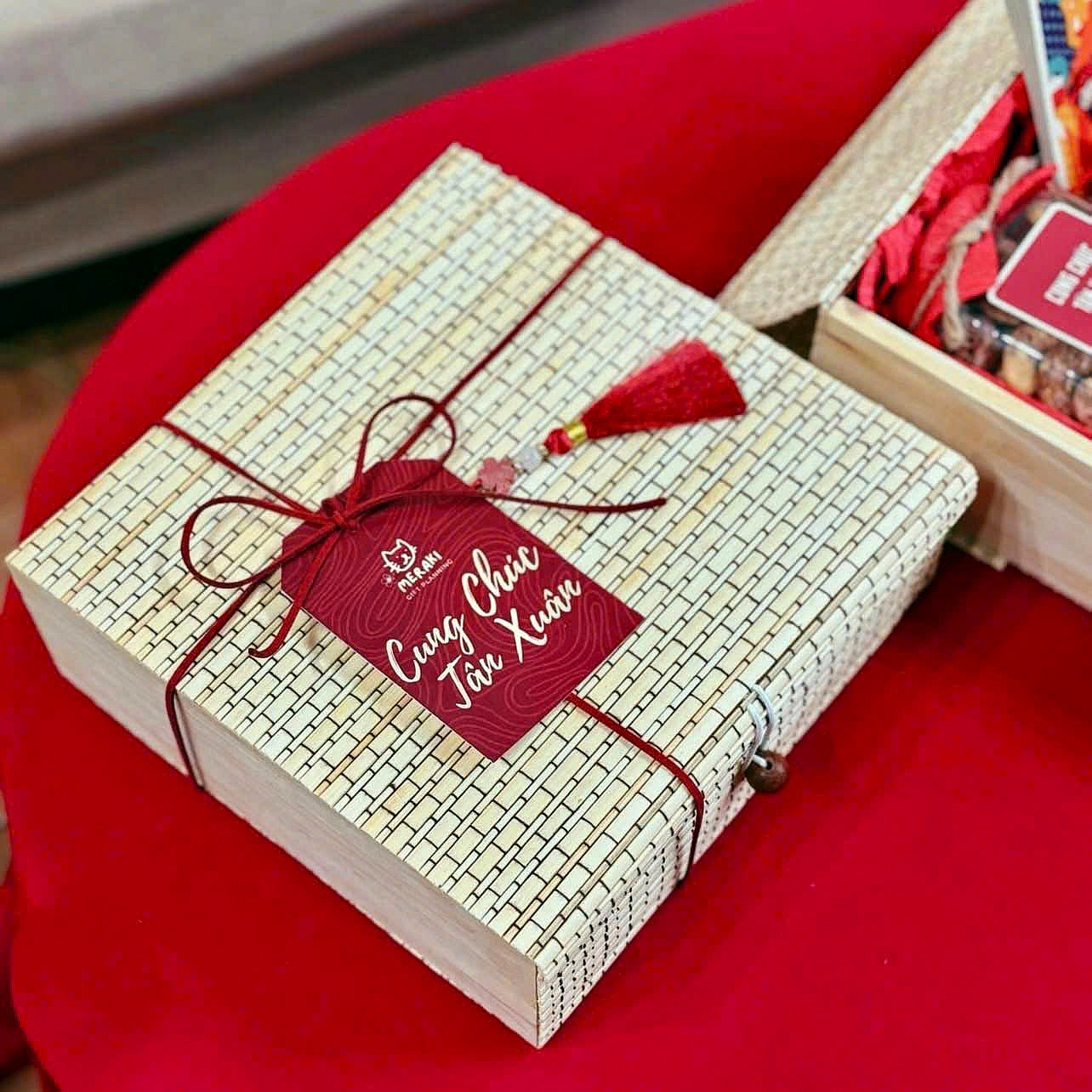 Woven bamboo Tet gift box tied with red cord and a New Year greeting tag