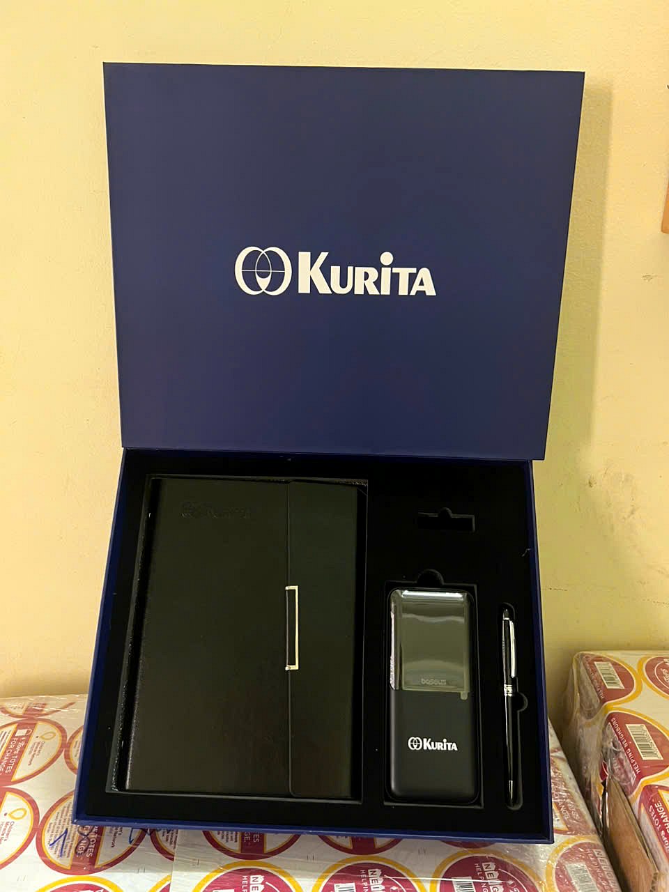 Kurita gift set with a navy box printed with the logo, black leather notebook, power bank and metal pen