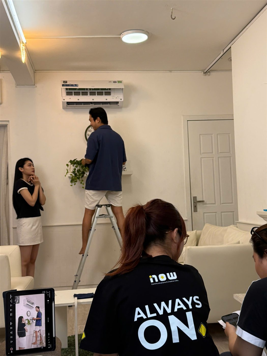 Now's crew staging a technician installing an AUX air conditioner in a living-room set