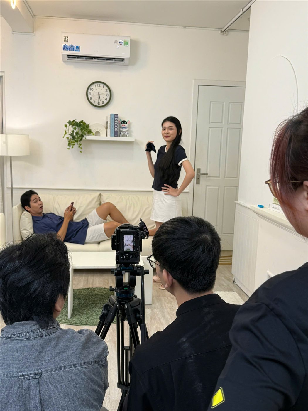 Actors performing an AUX air conditioner usage scene in a living room in front of Now's camera