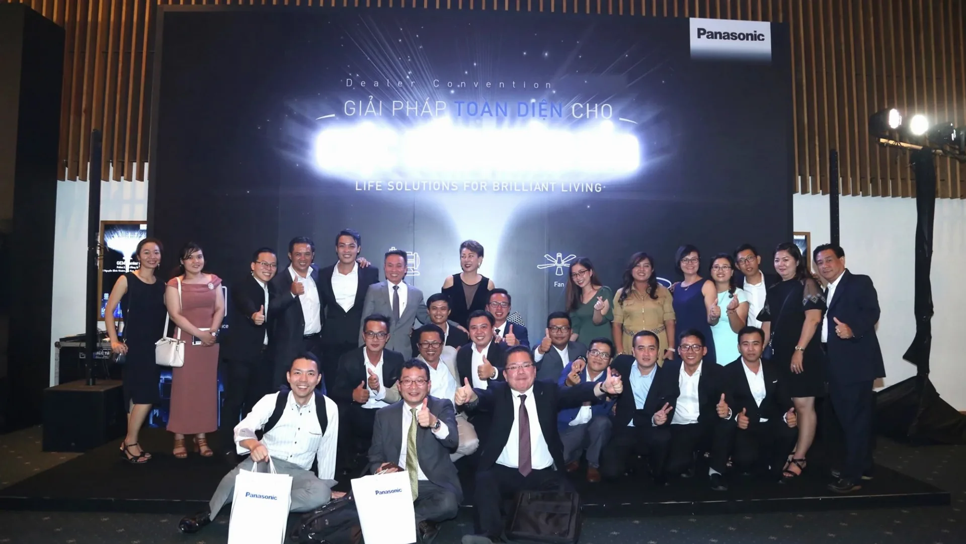 Dealer group taking a souvenir photo in front of the Panasonic conference key visual backdrop